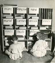 Deux enfants de maternelles, assis sur le sol, rangeant dans des casiers